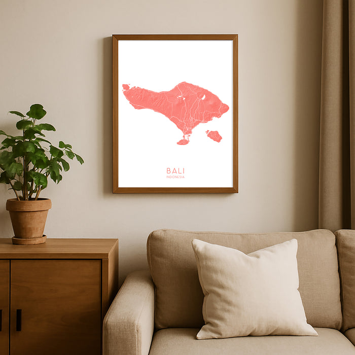 Framed map of Bali on a wall above a sofa with a plant beside it.