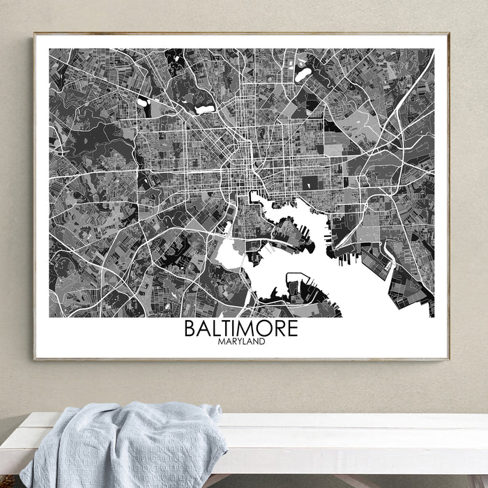 Framed black and white map of Baltimore on a wall above a white surface.
