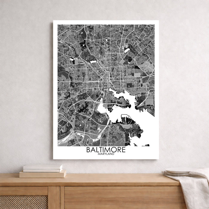 Framed black and white map of Baltimore on a wall above a wooden surface.