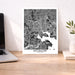 Framed map of Baltimore on a desk with a laptop and plant.