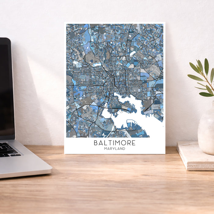 Framed map of Baltimore on a desk with a laptop and plant.