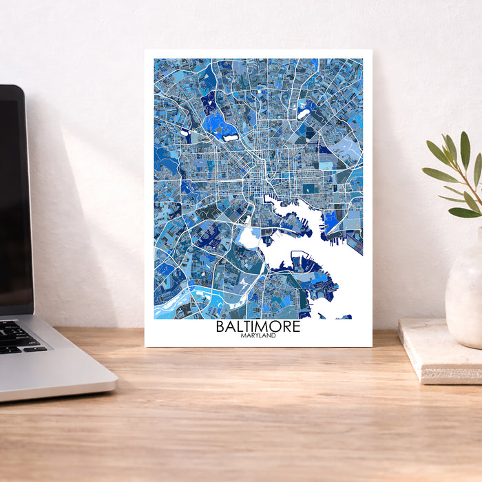 Framed map of Baltimore on a desk with a laptop and plant.