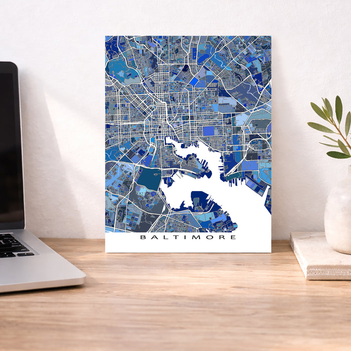 Map of Baltimore on a wall above a desk with a laptop and plant.