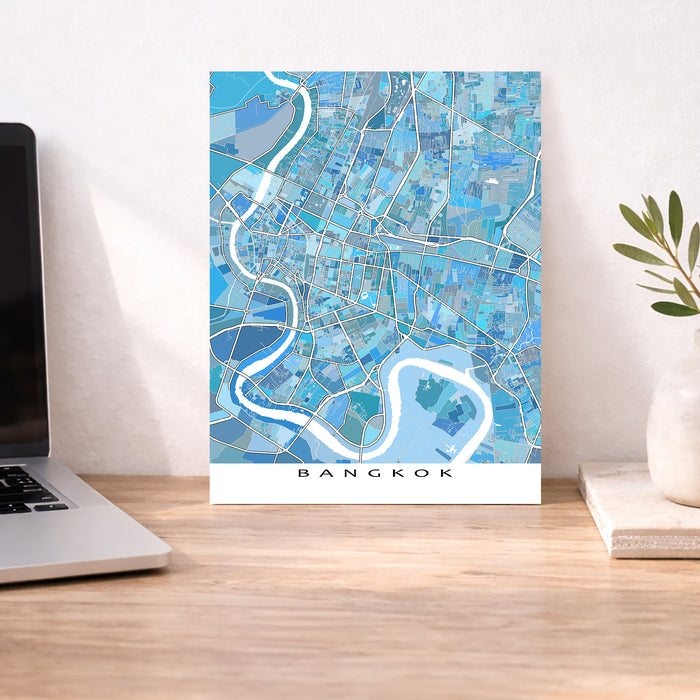 Map of Bangkok on a wall above a desk with a laptop and plant.