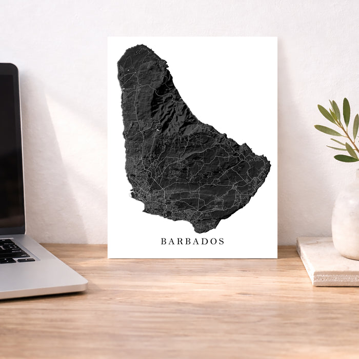 Map of Barbados on a white background with a laptop and plant in the background.