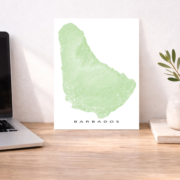 Map of Barbados on a desk with a laptop and plant