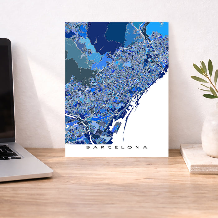 Map of Barcelona on a wall above a desk with a laptop and plant.