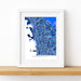 Framed map of Berkeley with a blue and white color scheme on a wooden surface.