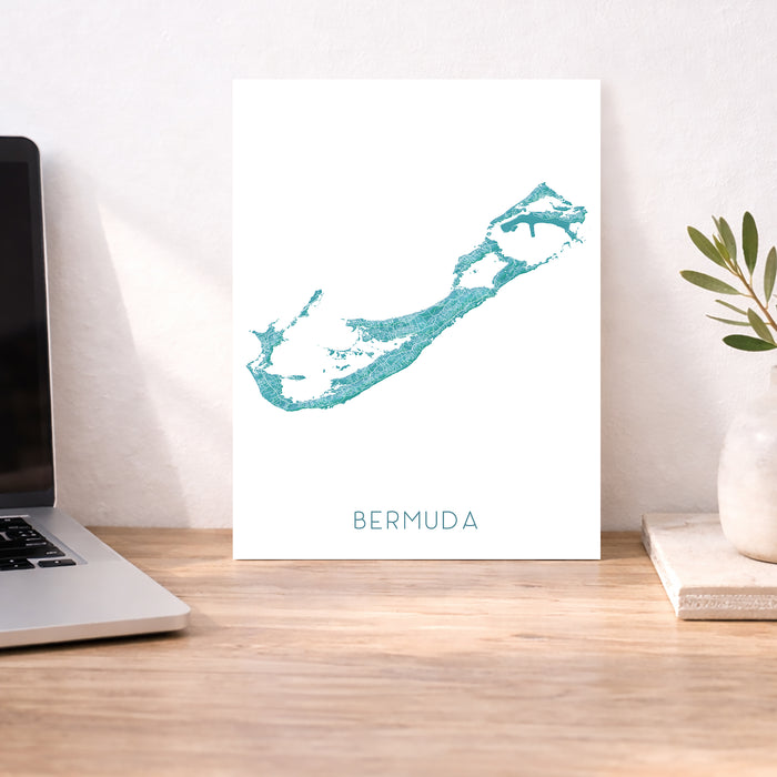 Desk with a laptop, plant, and a map of Bermuda on a white background