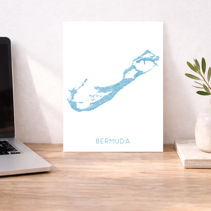 Map of Bermuda on a white background next to a laptop on a wooden desk.