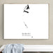 A framed minimalist black-and-white art print hanging on a beige wall above a white bench with a light blue draped cloth. The print features a stylized shark silhouette and the text 'BIMINI THE BAHAMAS'.