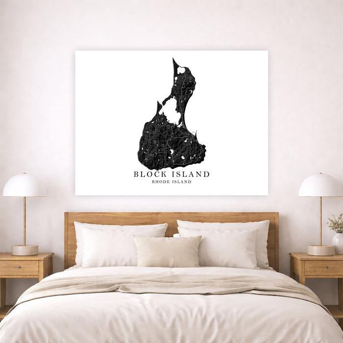 A black and white canvas print of Block Island, Rhode Island, styled on a light beige wall above a wooden bed with white and beige linens in a modern bedroom setting.