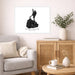 A framed black and white art print of Block Island, Rhode Island, displayed on a light beige wall in a styled living room setting with a gray armchair, wooden cabinet, and greenery.