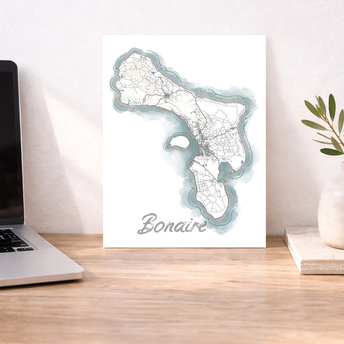 Map of Bonaire on a desk with a laptop and plant