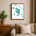 Framed map of Bora Bora on a wall above a sofa with a plant beside it.