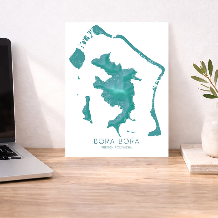 Map of Bora Bora on a desk with a laptop and plant