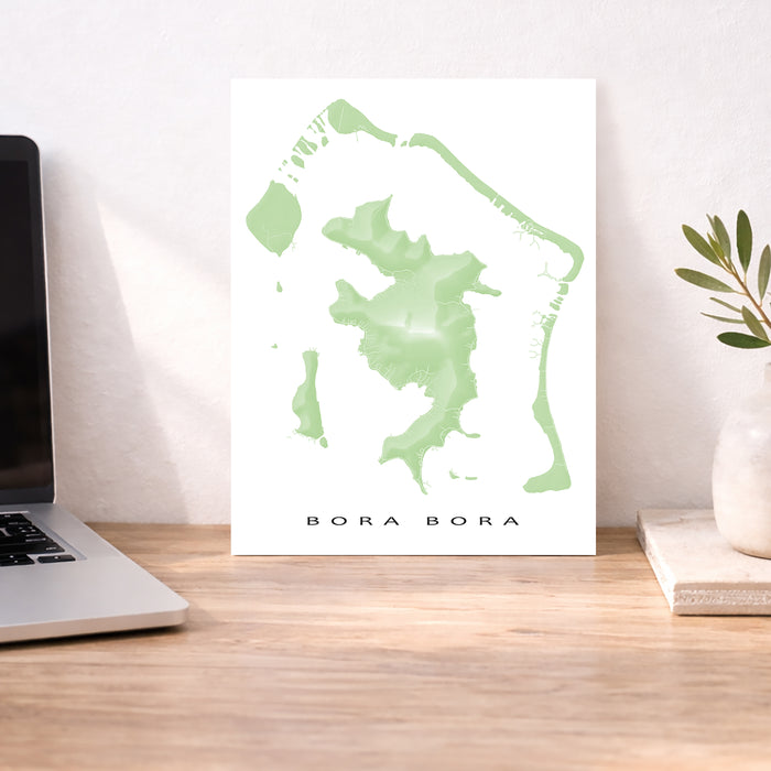 Map of Bora Bora on a desk with a laptop and plant