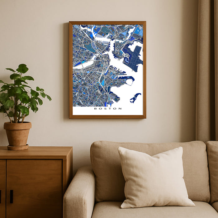 Framed map of Boston on a wall above a beige sofa with a plant beside it.