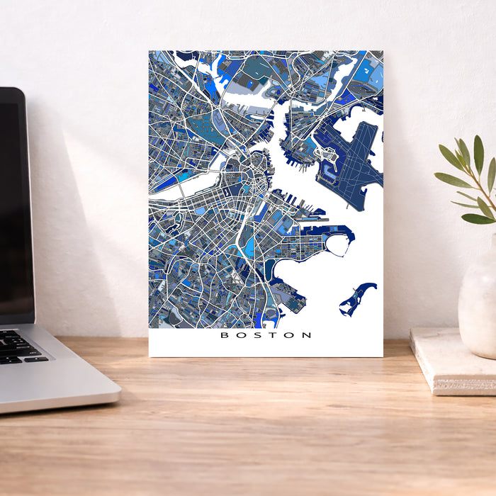 Map of Boston on a wall next to a laptop and plant