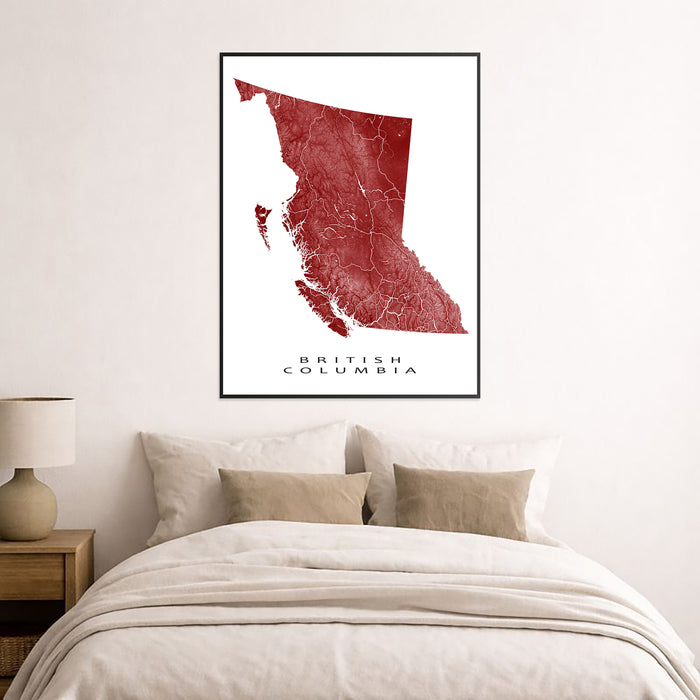 Framed map of British Columbia on a wall above a bed.