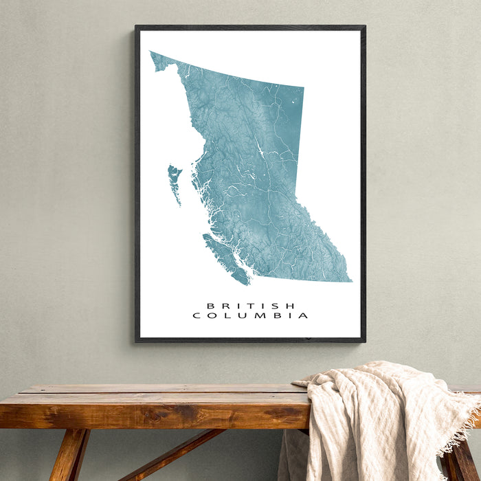 Framed map of British Columbia on a wall above a wooden bench.