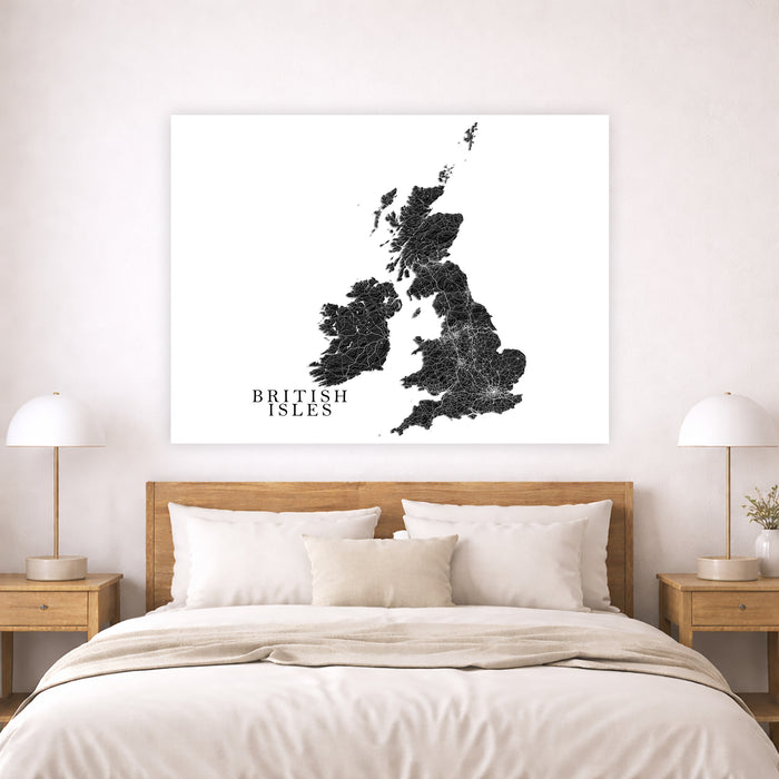 A large square wall art print featuring a black distressed map of the British Isles with the text 'BRITISH ISLES' on a white background, displayed above a neatly made bed in a modern bedroom setting.