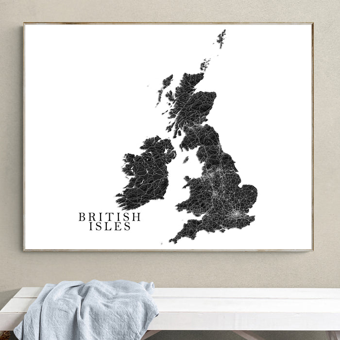 A framed black-and-white map print of the British Isles hangs on a beige wall above a white bench with a light blue cloth draped over it.