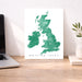 Map of the British Isles on a white background, displayed on a wooden desk with a laptop and plant.