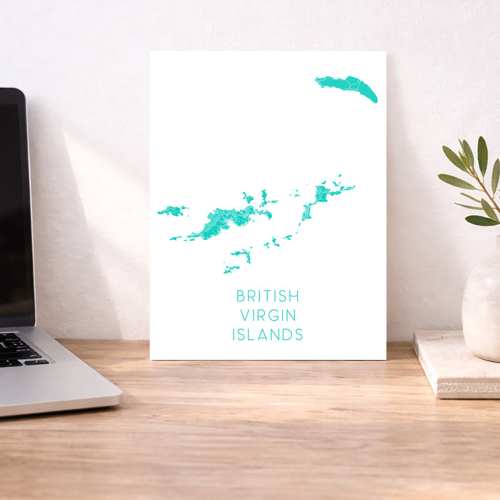 Map of British Virgin Islands on a white background, displayed on a wooden desk with a laptop and plant.