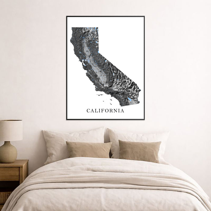 Framed map of California on a wall above a bed in a bedroom.