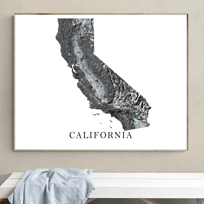 Framed map of California on a wall above a white bench.