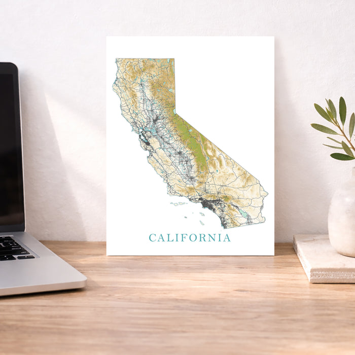 Map of California on a desk with a laptop and plant