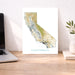 Map of California on a desk with a laptop and plant