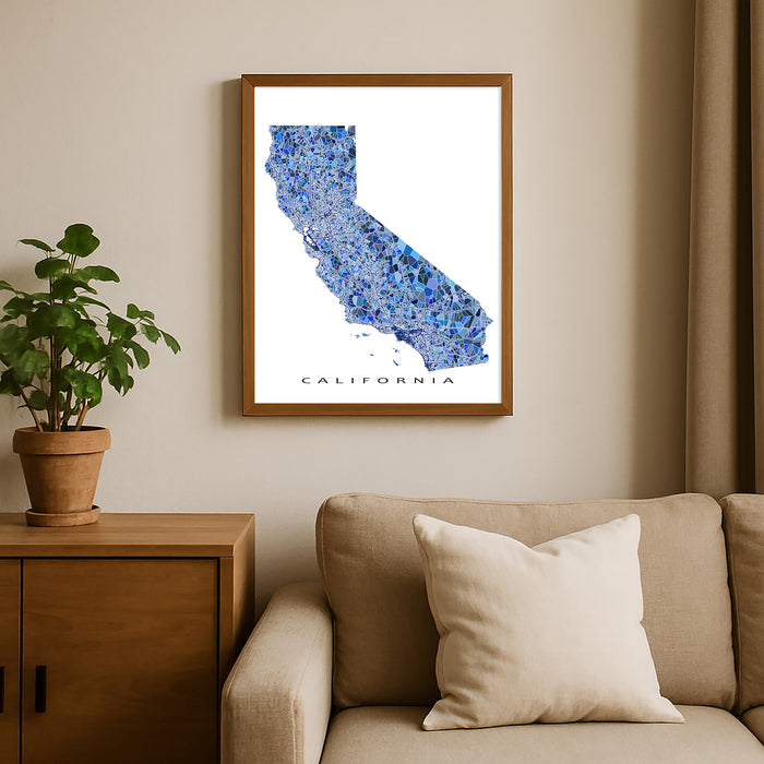 Framed map of California on a wall above a beige sofa with a plant beside it.