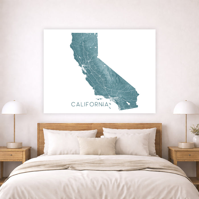 Framed map of California on a wall above a bed with wooden headboard and nightstands.