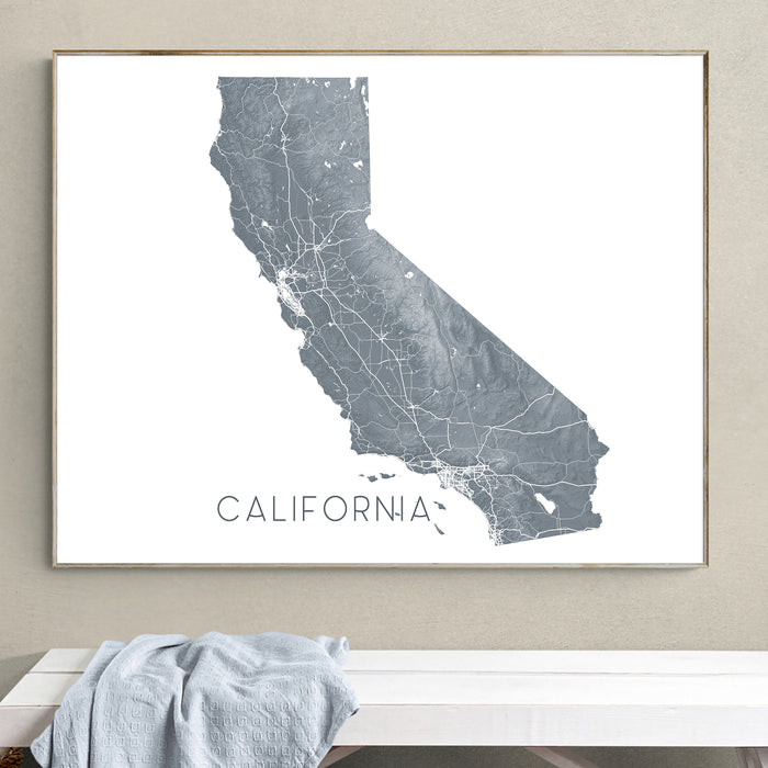 Framed map of California on a wall above a white bench.