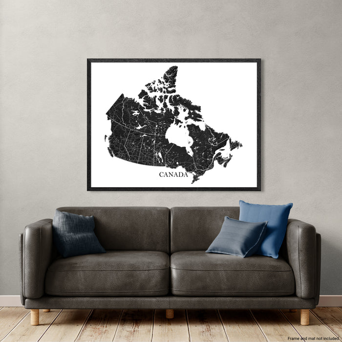 Framed map of Canada above a gray sofa with blue pillows on a light gray wall.
