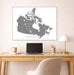 Map of Canada on a wall above a desk with a laptop and lamp.