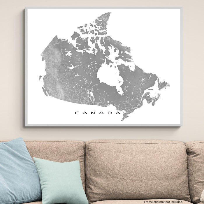 Framed map of Canada on a wall above a beige sofa with light blue pillows.