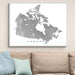 Framed map of Canada on a wall above a beige sofa with light blue pillows.
