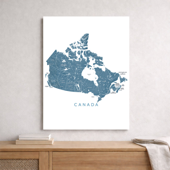 Map of Canada on a white background, displayed on a wall above a wooden shelf.