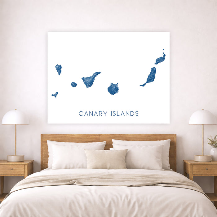 Map of the Canary Islands on a wall above a bed in a bedroom.