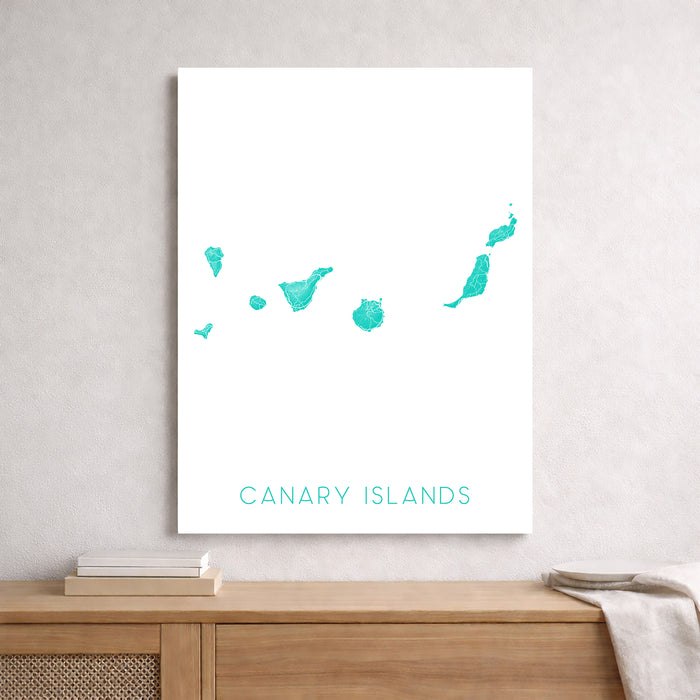 Map of the Canary Islands on a white wall above a wooden shelf.