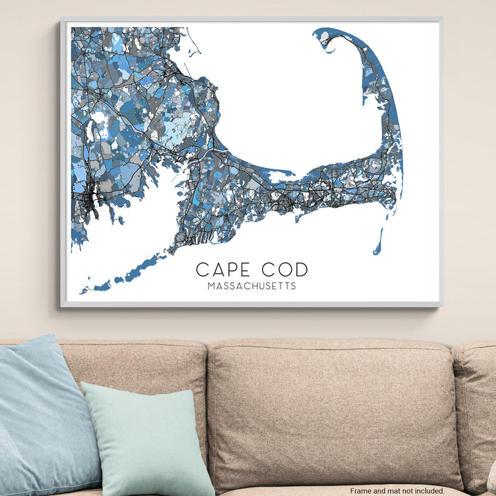 Framed map of Cape Cod, Massachusetts on a wall above a beige sofa with light blue pillows.