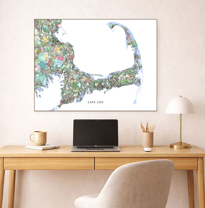 Desk with laptop, mug, and lamp, featuring a colorful map of Cape Cod on the wall.