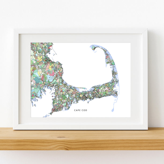 Framed map of Cape Cod on a white wall with a wooden shelf.