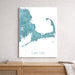 Map of Cape Cod in teal and white on a light gray wall above a wooden shelf.