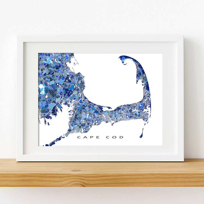 Framed artwork of a blue and white map of Cape Cod on a wooden shelf.