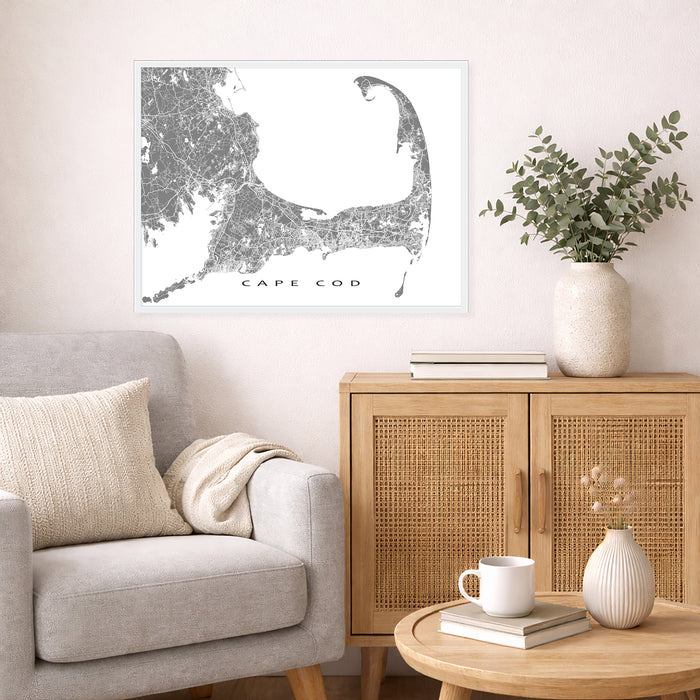 Living room with a map of Cape Cod on the wall, a light gray sofa, wooden cabinet, and small table.