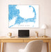 Framed map of Cape Cod above a desk with a laptop and lamp.